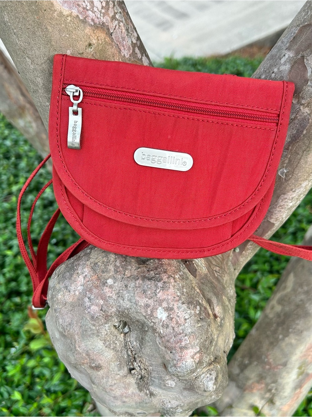 Baggallini Teenee red crossbody travel bag with a silver logo plate.